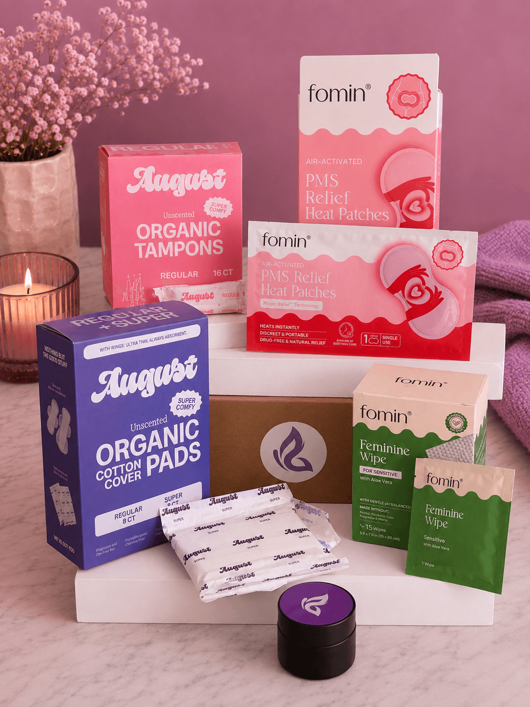 Solace subscription box surrounded by organic tampons and pads, PMS relief heat patches, feminine wipes and a Solace balm tin
